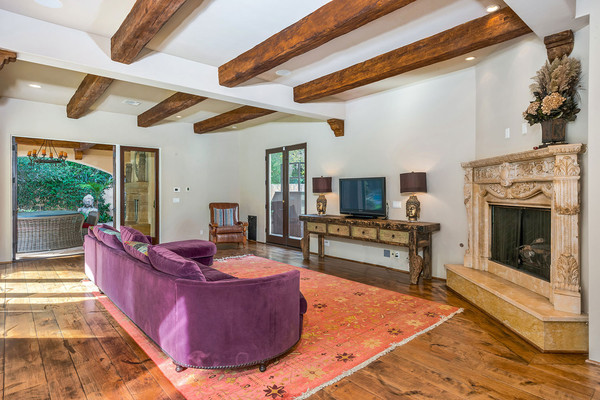 کاناپه راحتی از جنس مخمل و به رنگ بنفش در کنار شومینه، فضایی راحت برای تماشای اخبار یا ویدئوهای موسیقی را تشکیل داده اند.