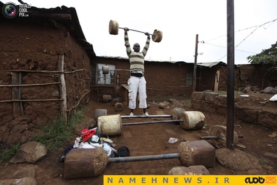 یک جوان اهل نایروبی در حال تمرین با وزنه های سنگین ساخته شده با پیت حلبی 